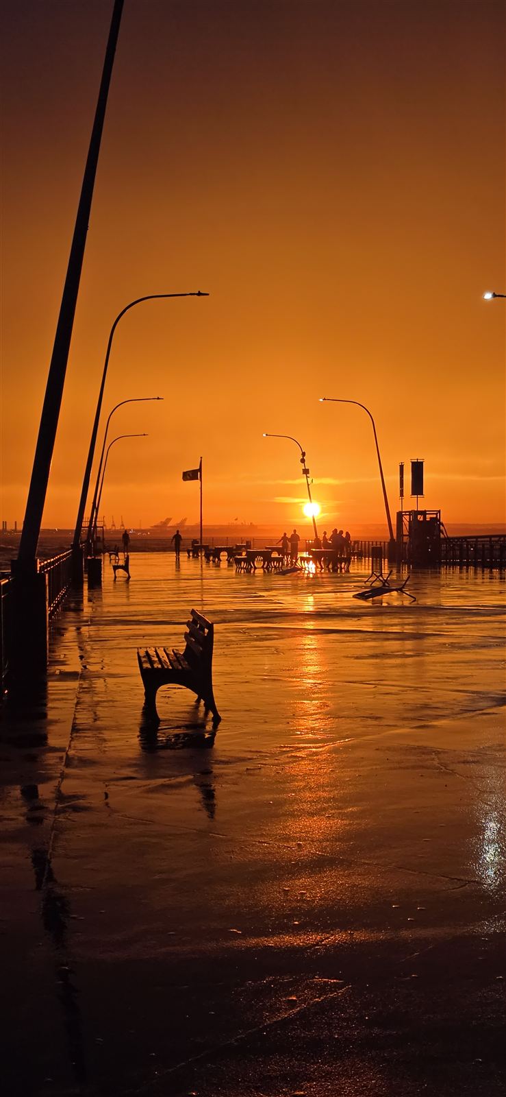 A beach pier silhouetted in golden sunset light