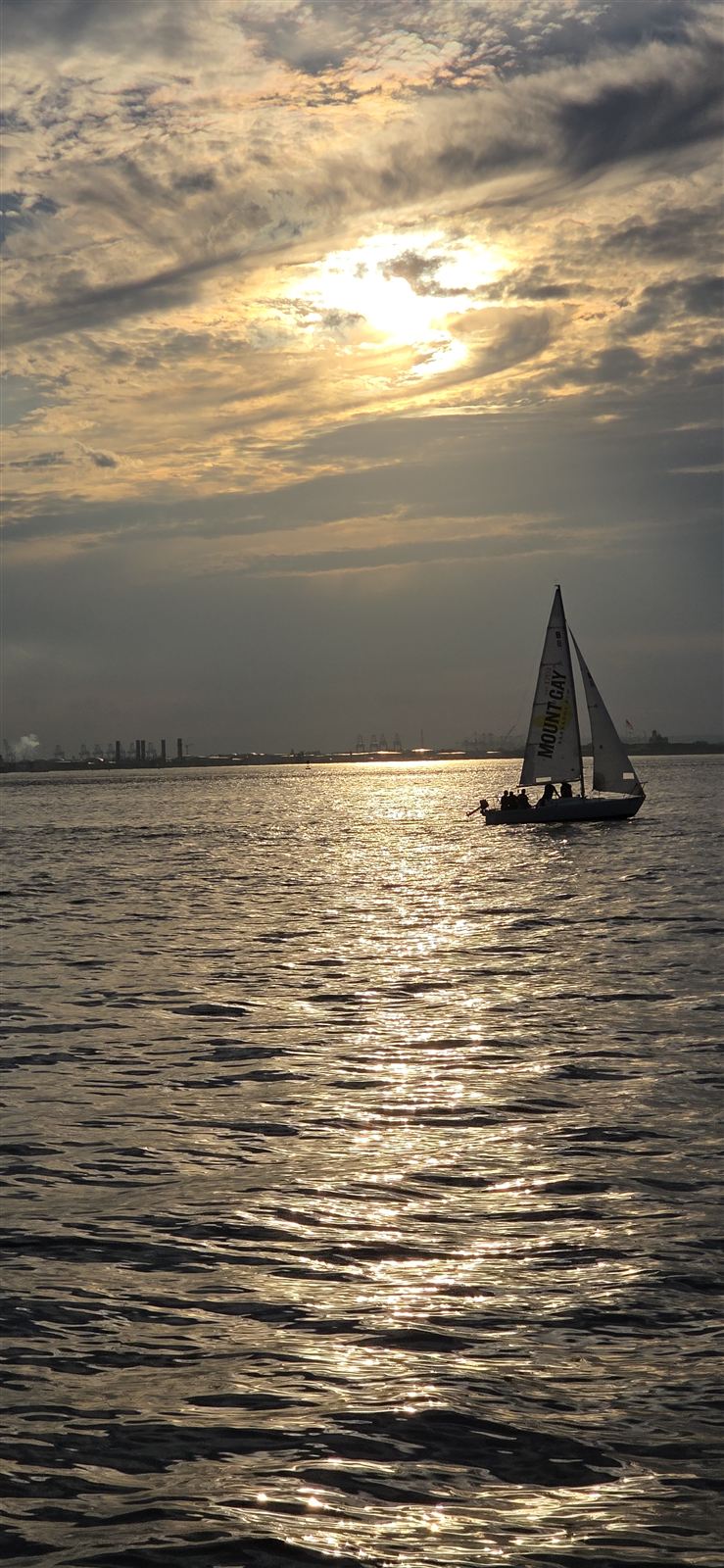 A sailboat on glittering water at sunset